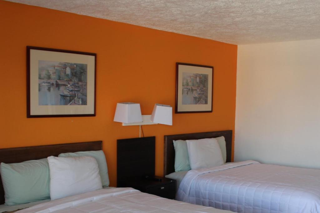 2 Betten in einem Hotelzimmer mit orangefarbenen Wänden in der Unterkunft Americas Best Value Inn & Suites Williamstown in Williamstown