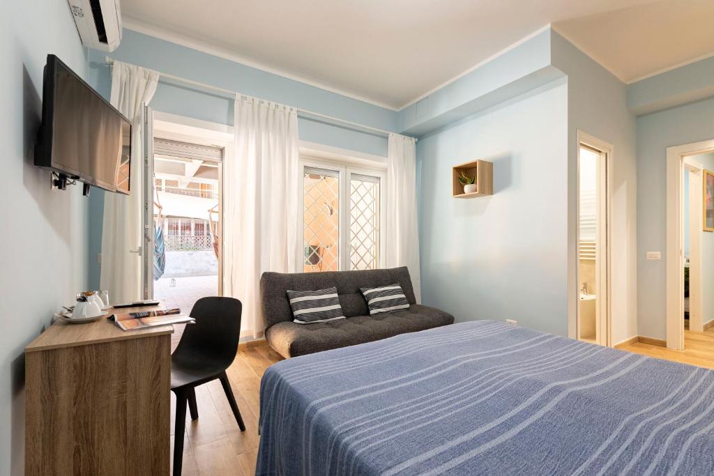 a bedroom with a bed and a couch and a television at RomeCookSea Guesthouse in Lido di Ostia