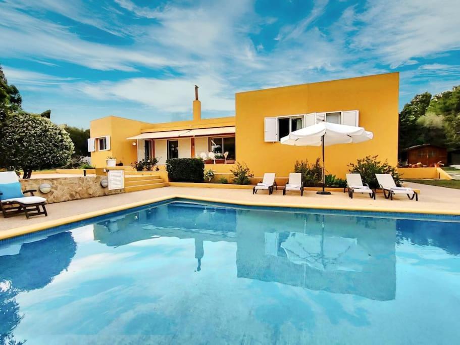 a pool with chairs and an umbrella in front of a house at Bonita Casa con piscina privada y amplio jardin in Sant Francesc de s'Estany