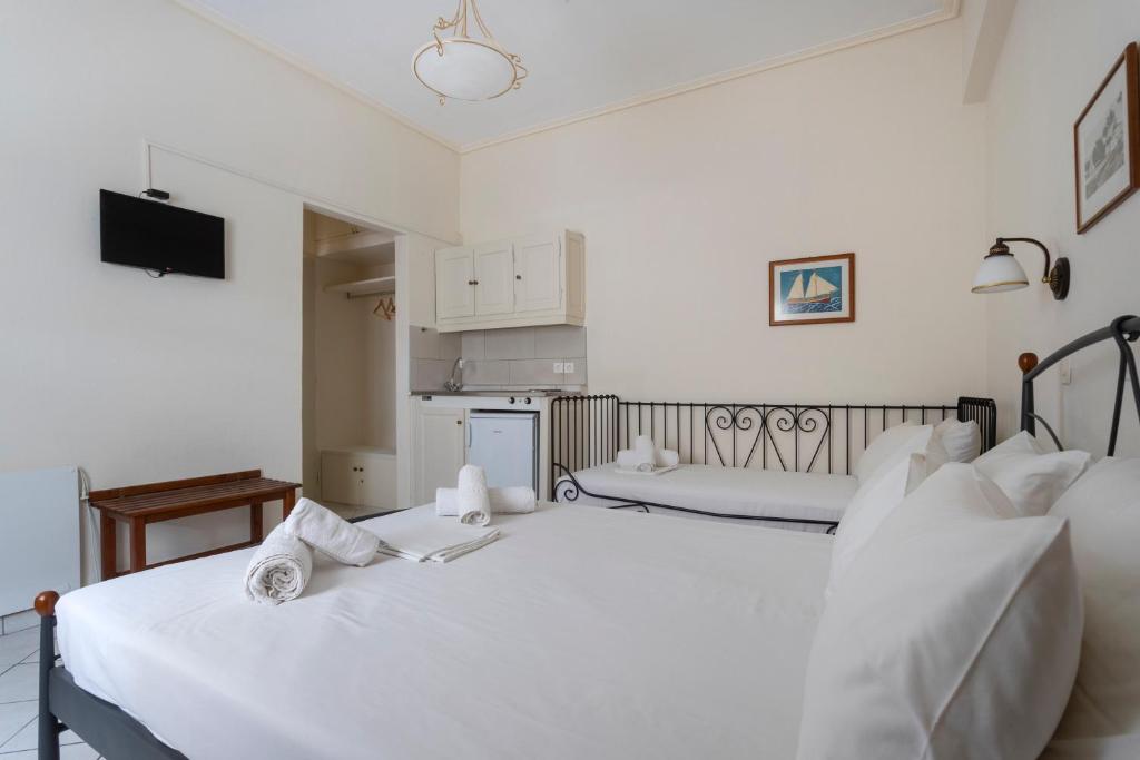 a white bedroom with two beds and a kitchen at Villa Kalomira in Spetses