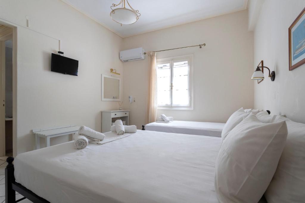 a white bedroom with two beds and a window at Villa Kalomira in Spetses