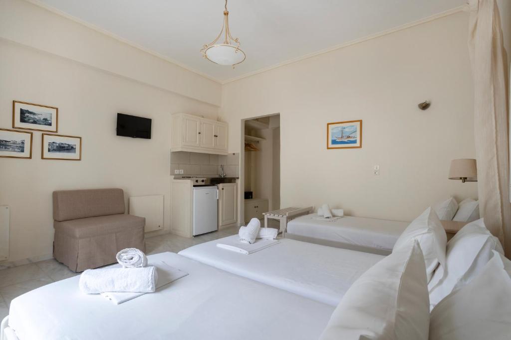 a white room with two beds and a chair at Villa Kalomira in Spetses
