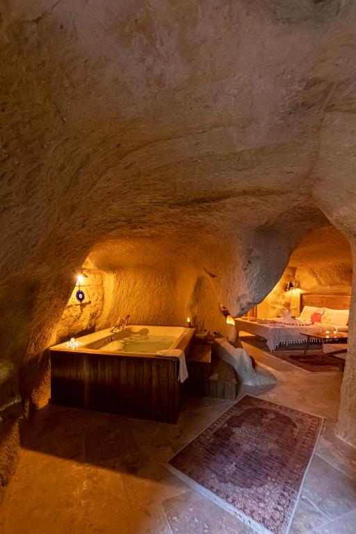 a room with a tub in a cave with two beds at feris cave hotel in Urgup