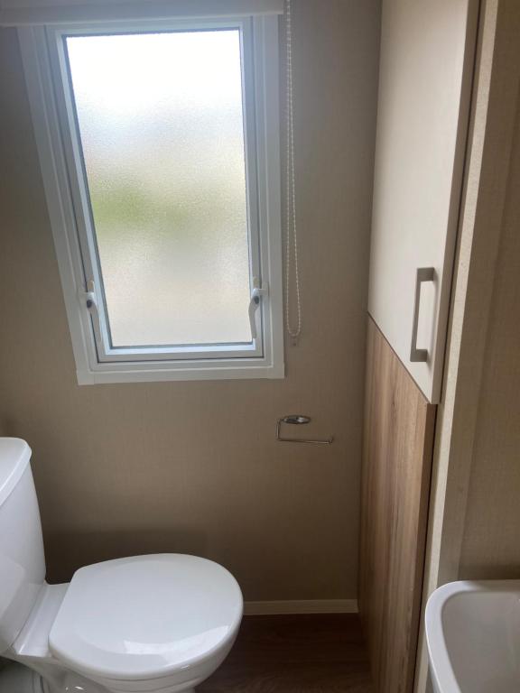 a bathroom with a toilet and a window at The Oakley golden sands rhyl in Kinmel Bay