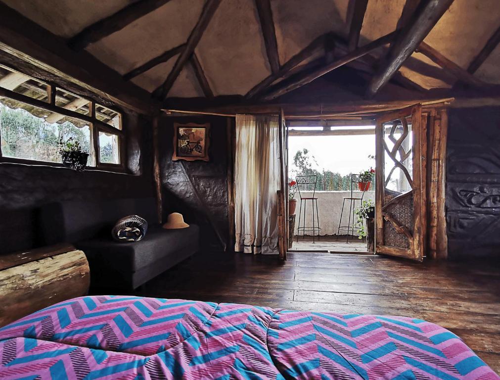 um quarto com uma cama e uma porta para um pátio em Allpa Wasi - Casa Suaya La Esperanza em Ibarra