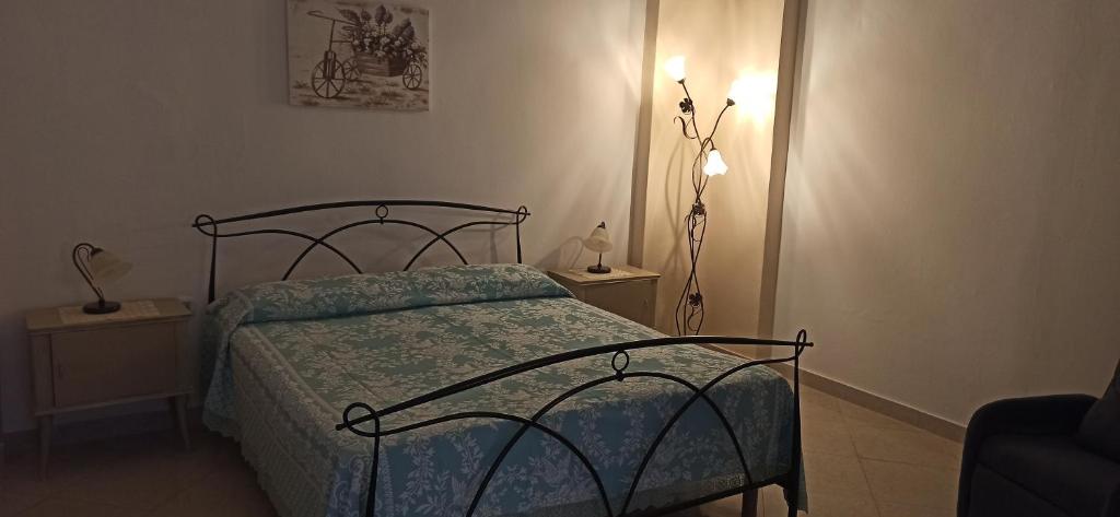 een slaapkamer met een bed met een blauw dekbed en een lamp bij La dimora dei nonni in Tuglie