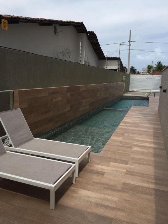 a swimming pool with two lounge chairs on a house at Lindo apartamento de férias à 100m do mar! in Cabedelo