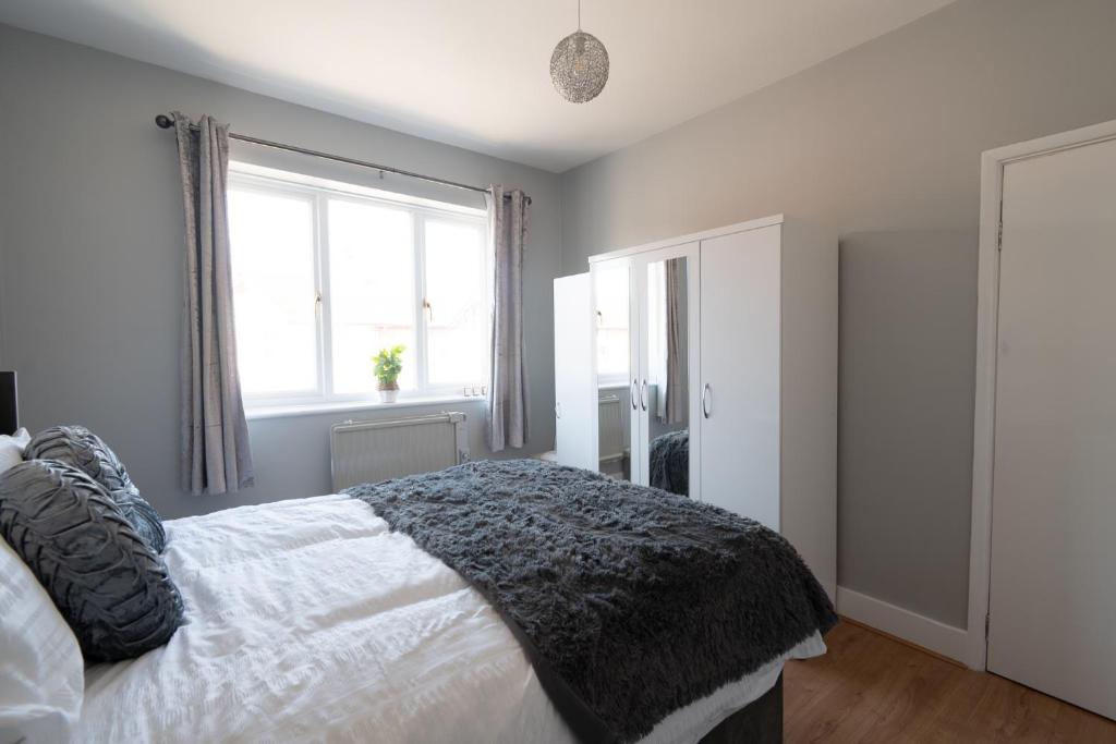 a bedroom with a white bed and a window at Elmcroft Apartment - 10 Mins Walk to Woking Town Centre in Woking