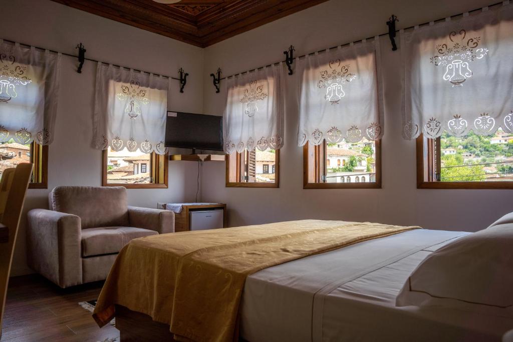 a bedroom with a bed and a chair and windows at Hotel Borklad in Berat