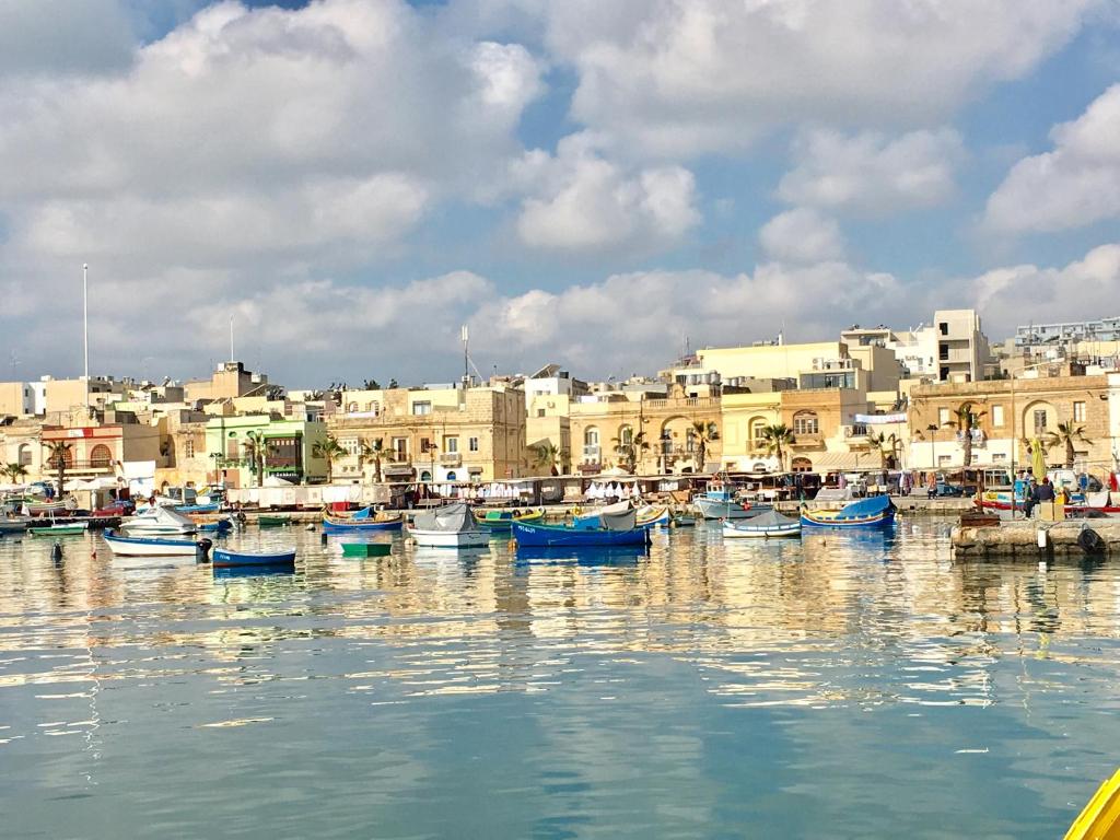 um grupo de barcos ancorados num porto com edifícios em ONE100 apartments em Marsaxlokk