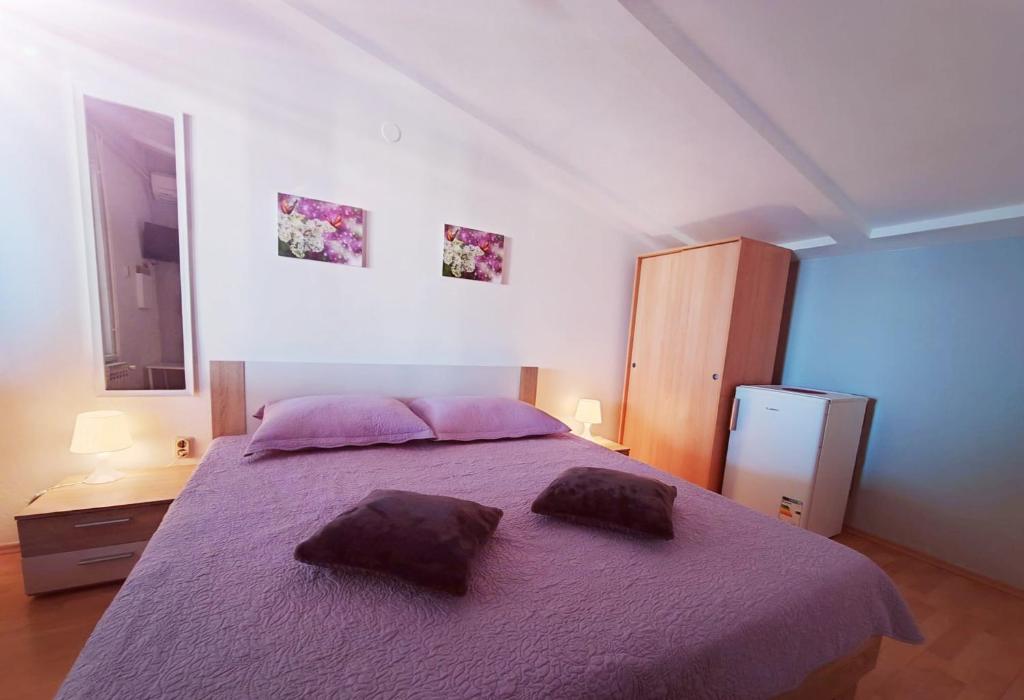 ein Schlafzimmer mit einem lila Bett mit zwei Kissen darauf in der Unterkunft Guesthouse Resan in Medulin