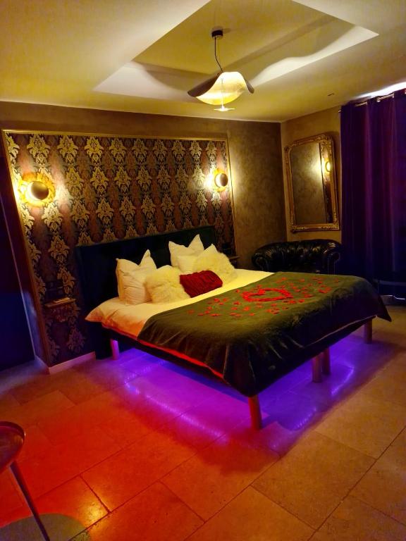 une chambre avec un grand lit avec des lumières violettes dans l'établissement L'Aphrodite Jacuzzi privatif, à Saint-Zacharie