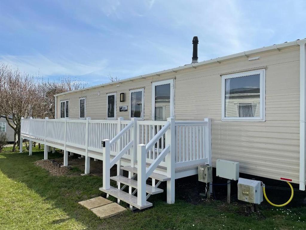 a mobile home with a porch and a white railing at Emma's Oasis 4-bedroom caravan at Durdle Door in West Lulworth