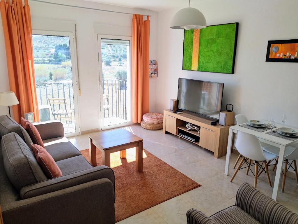 ein Wohnzimmer mit einem Sofa, einem TV und einem Tisch in der Unterkunft Apartment-in-turre-andalucia in Turre