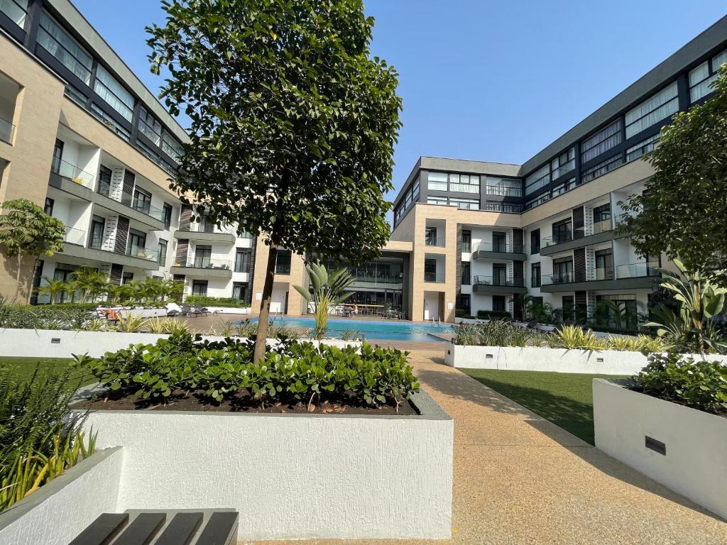 um edifício de apartamentos com uma árvore num pátio em Embassy Gardens Suites by Olive Gold em Cantonments