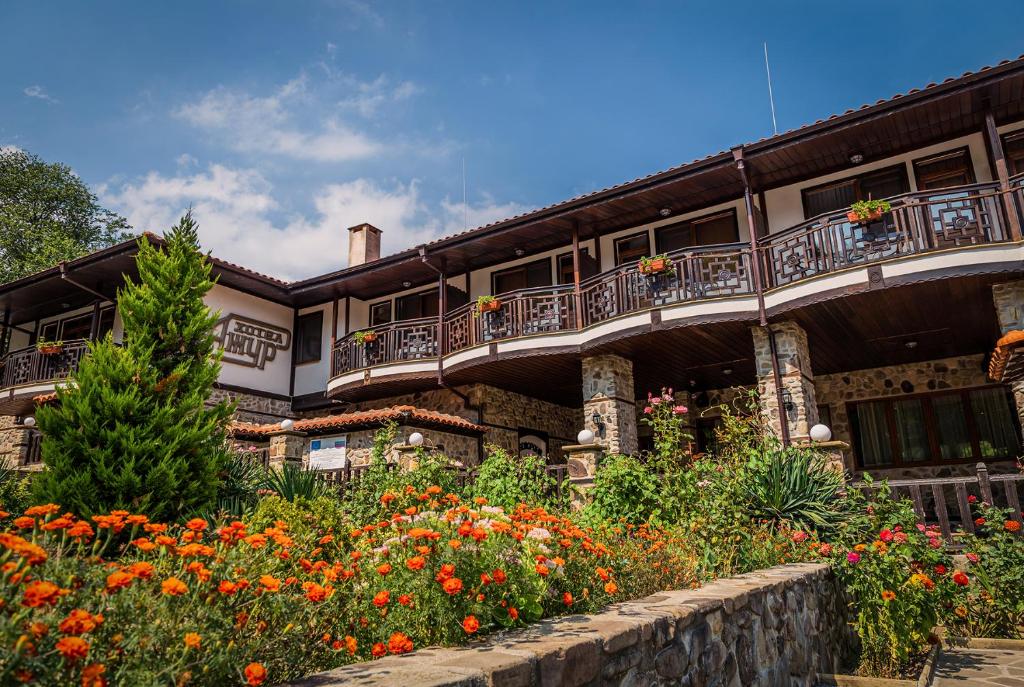 un edificio con balcón y un jardín de flores en Хотел Ажур en Kotel