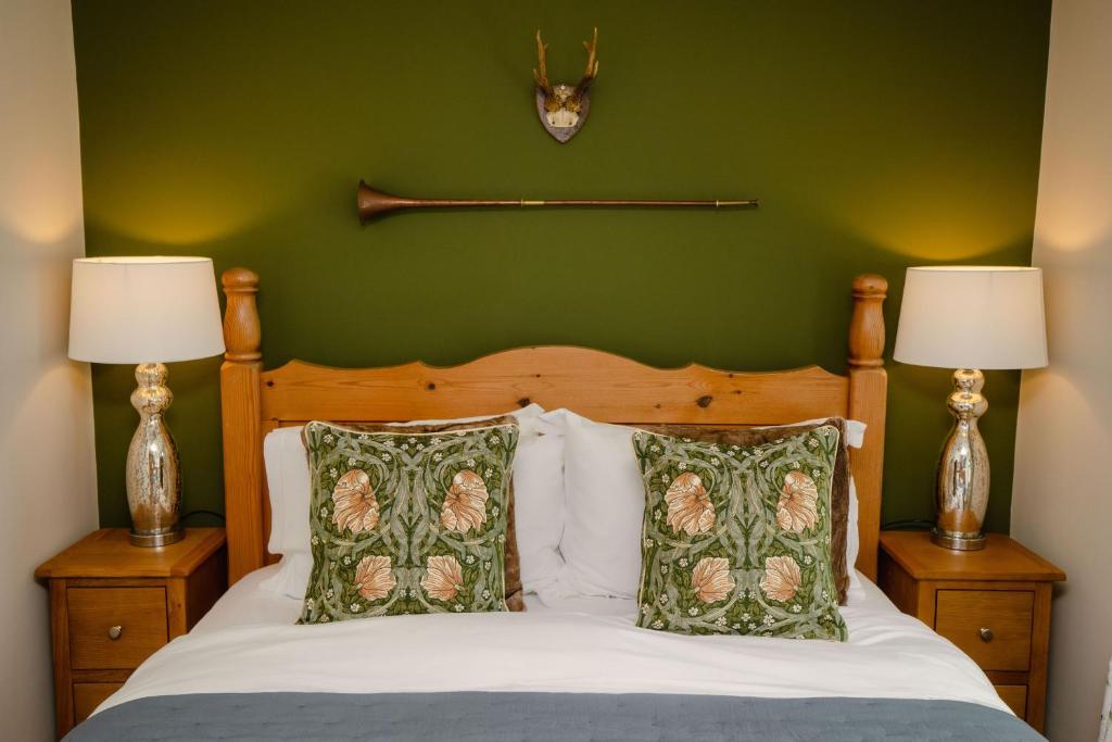 ein grünes Schlafzimmer mit einem Bett mit zwei Lampen in der Unterkunft Carters Cottage - Rudge Farm Cottages in Bridport