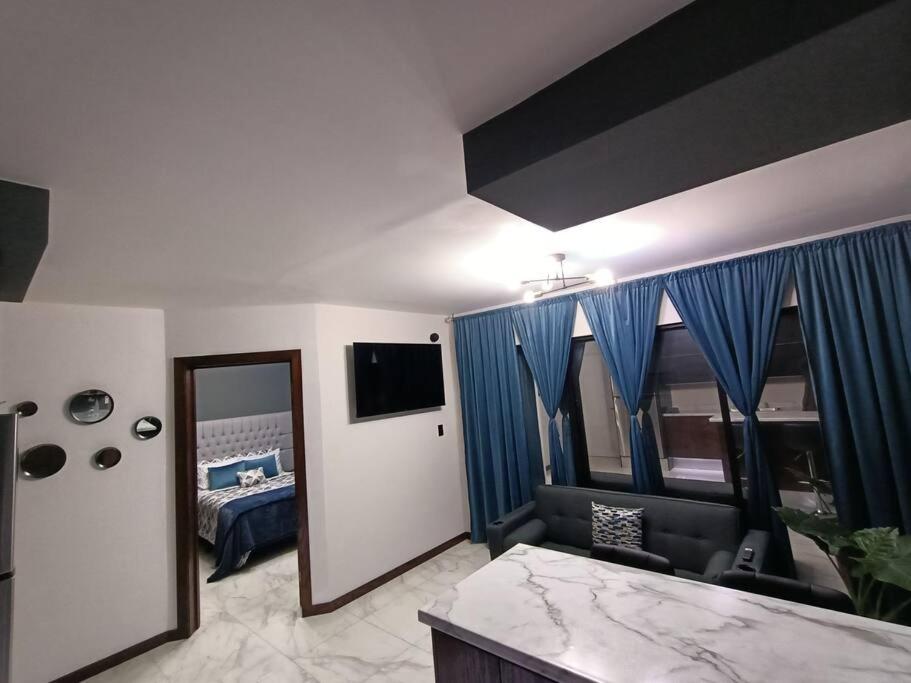 1 dormitorio con cama, cortinas azules y espejo en moderno apartamento en el centro de la ciudad, en Chihuahua