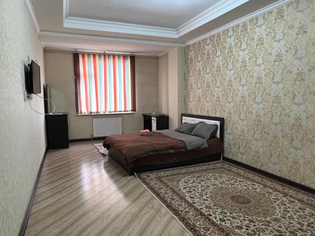 ein Schlafzimmer mit einem Bett und einem großen Fenster in der Unterkunft apartment on Turusbekova 13 in Bischkek