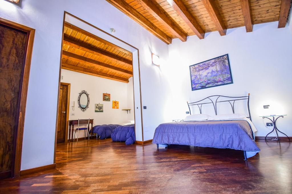 een slaapkamer met een bed en een houten vloer bij Case Ruggero in Cefalù