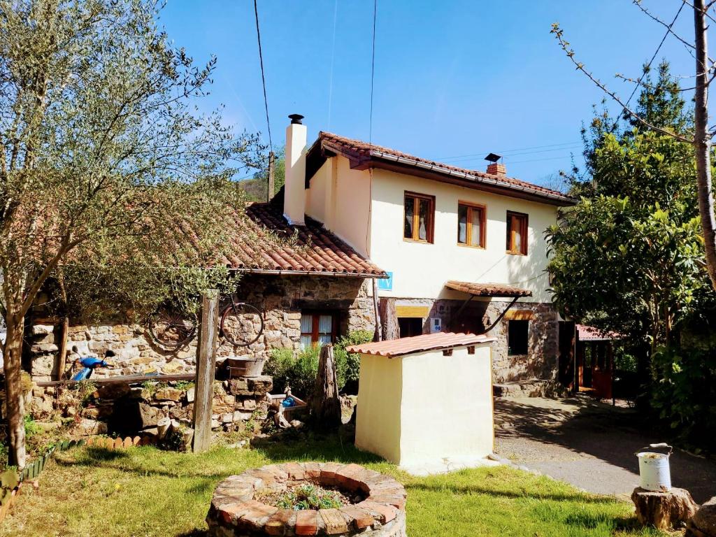 una antigua casa de piedra con un jardín delante de ella en Casa Ferreira, Senda del Oso, en Oviedo