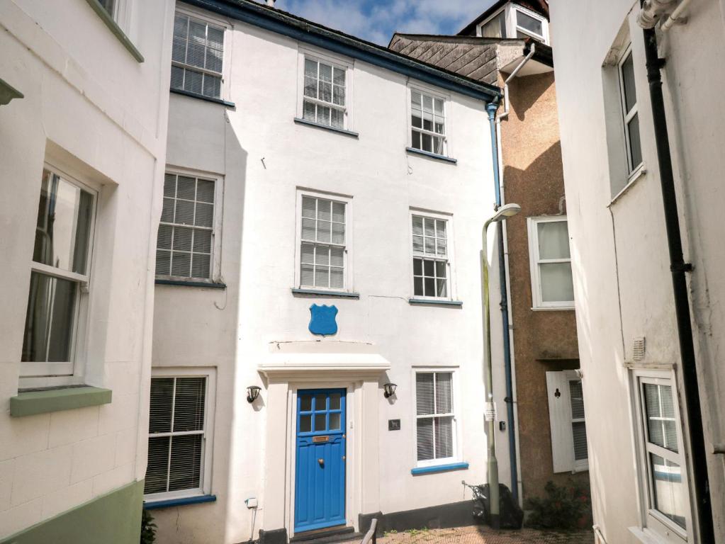 ein weißes Haus mit blauer Tür auf einer Straße in der Unterkunft Grants Cottage in Dartmouth