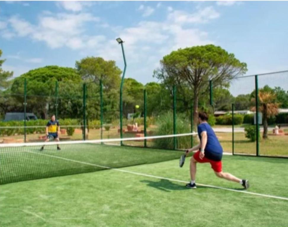 two people playing tennis on a tennis court at Camping Oasis village in Puget-sur-Argens