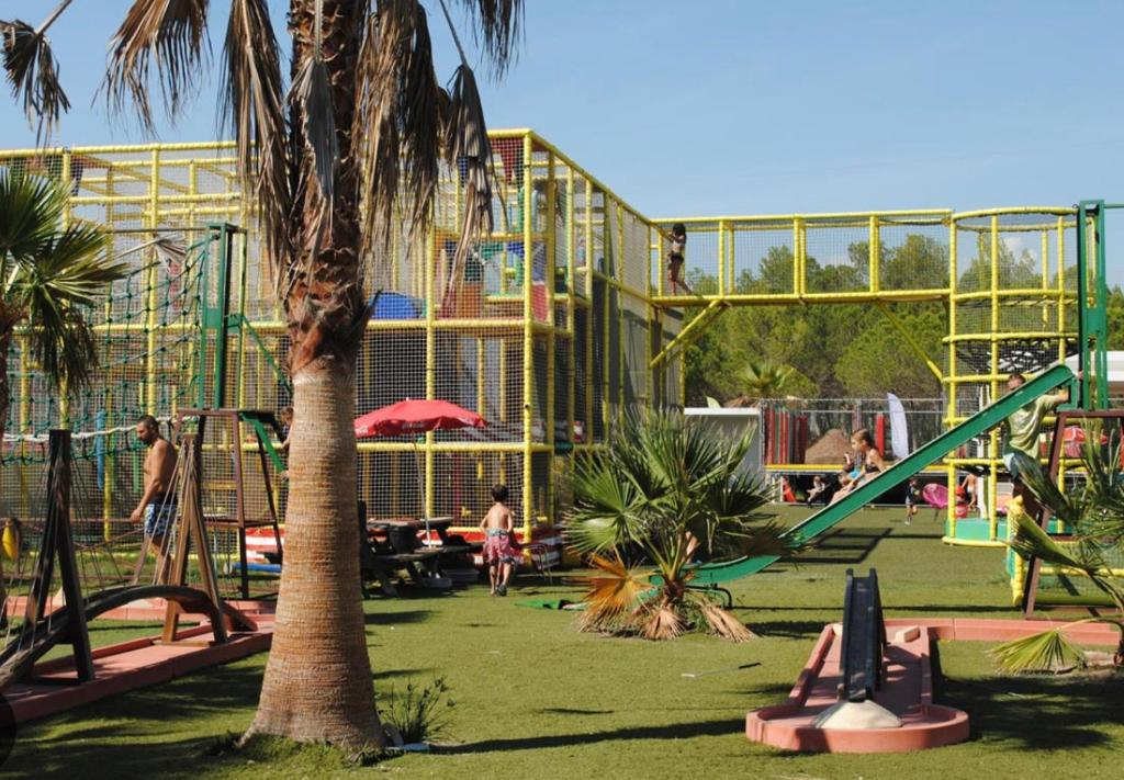 a playground in a park with people playing in it at Camping Oasis village in Puget-sur-Argens