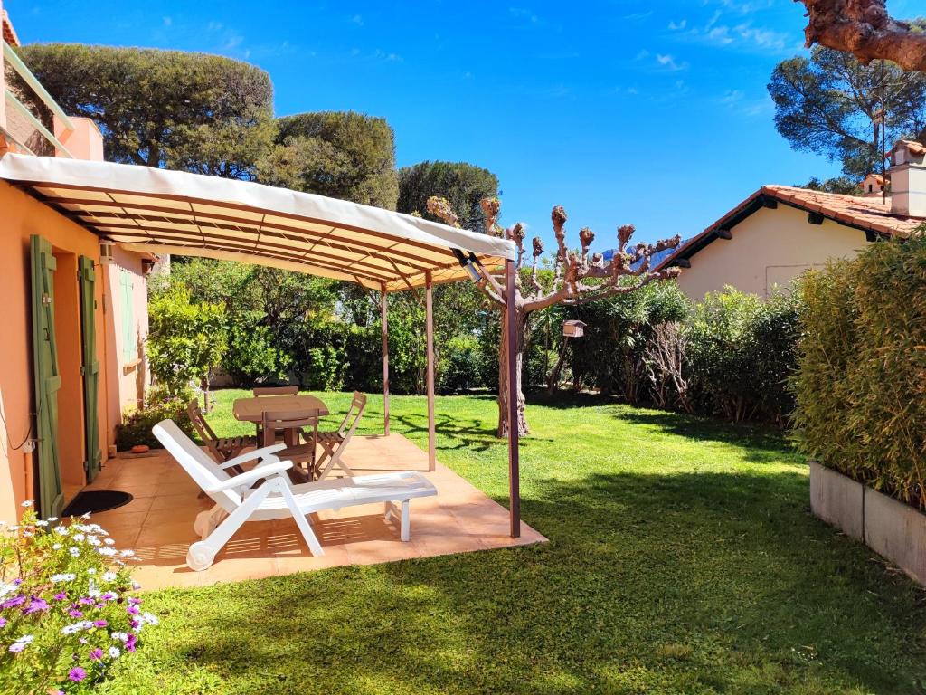 a patio with a table and a chair under a canopy at Côté Jardin - T2 avec Terrasse Couverte et Jardin in Cassis