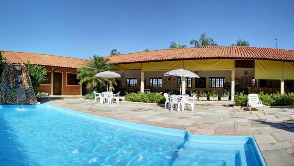a resort with a pool and chairs and umbrellas at Pousada do Sol in Brotas
