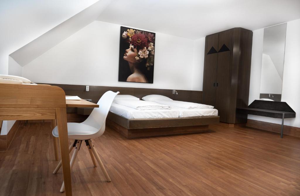a bedroom with a bed and a table and a painting at Stadthotel Heilbronn in Heilbronn