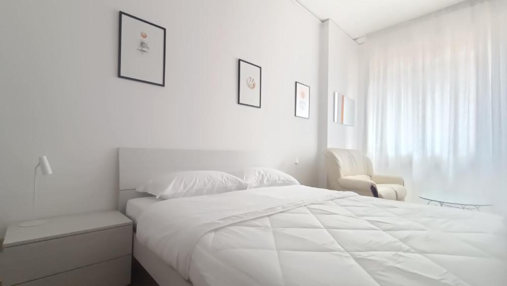 a white bedroom with a white bed and a chair at Sleep&Go - Appartamento in Florence