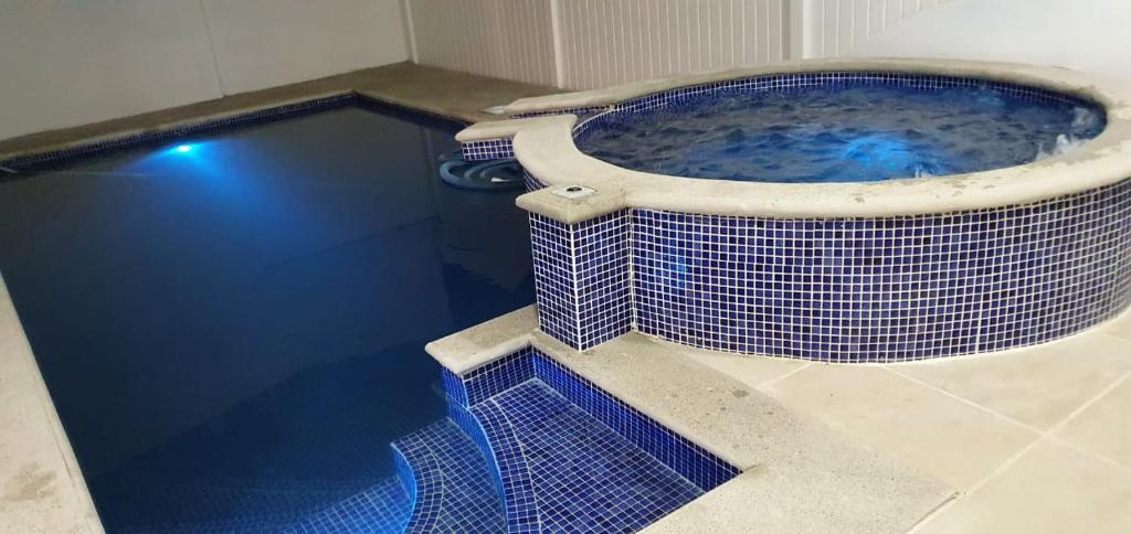 y baño con bañera grande con azulejos azules. en Casa de playa con piscina y jacuzzi privado, en Puntarenas