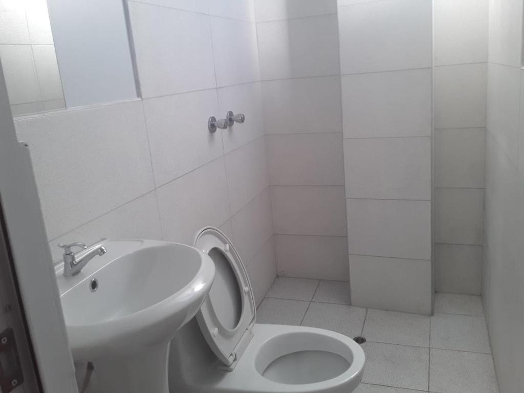 a white bathroom with a toilet and a sink at Roma Hostal in Juliaca