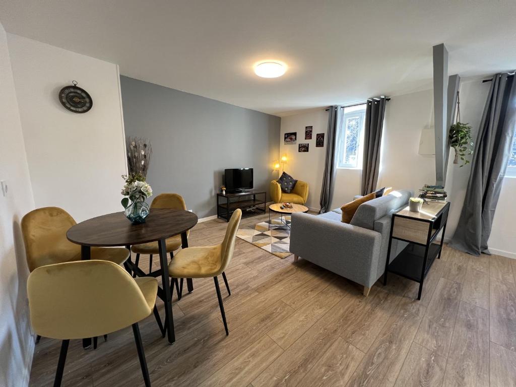 uma sala de estar com uma mesa e cadeiras e um sofá em Nid douillet T2 rénové climatisé centre em Brive-la-Gaillarde