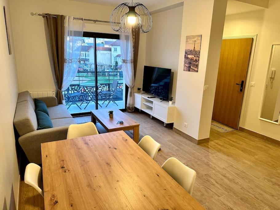uma sala de estar com uma mesa de madeira e um sofá em Appartement à 15min de paris em Drancy