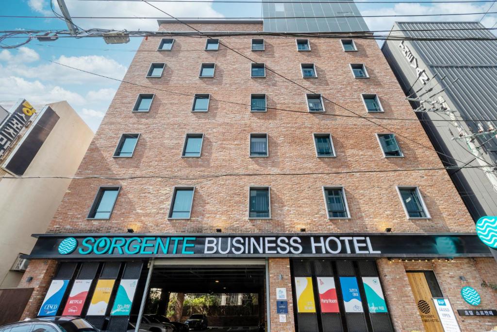 a large brick building with a sign on it at Sorgente Business Hotel in Busan