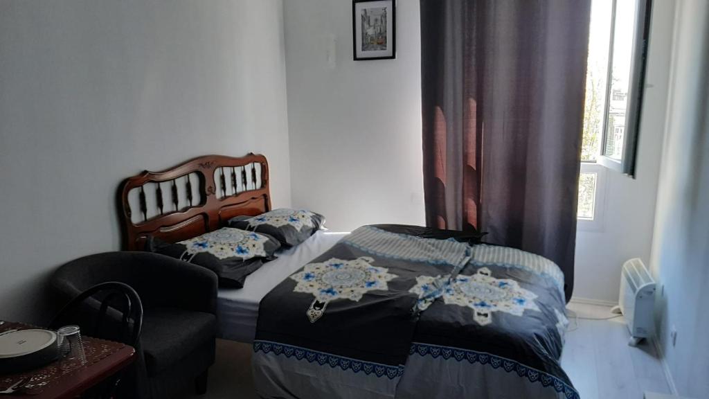 塞爾吉的住宿－STUDIO TRES PROPRE de 18 m2，一间卧室设有两张床、一把椅子和一个窗户。