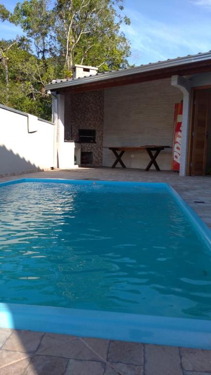 a blue swimming pool in front of a house at Casa com piscina - Itapoá in Itapoa