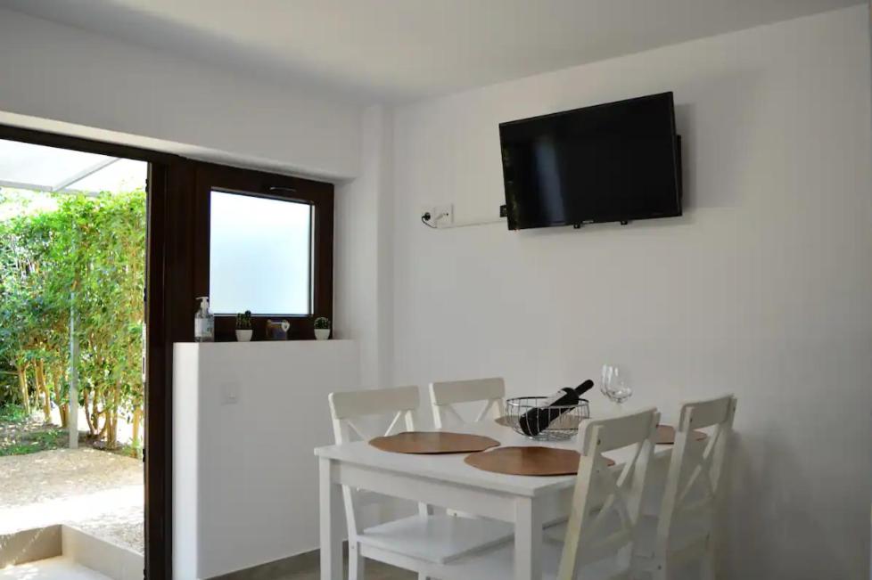 biała jadalnia z białym stołem i krzesłami w obiekcie Calma Kourouta Apartments w mieście Kourouta