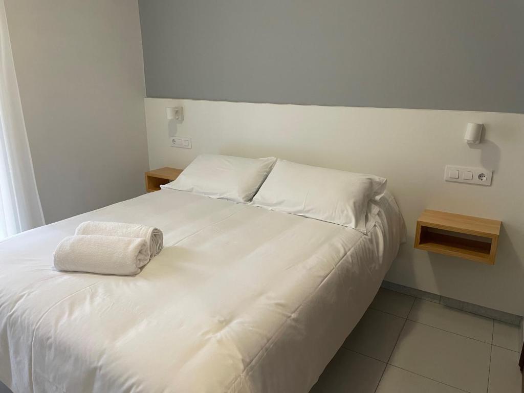 un letto bianco con due cuscini sopra di Hotel Venezuela a Sanxenxo