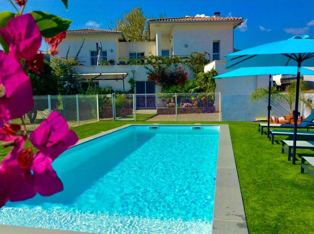 una piscina frente a una casa con flores rosas en Les bougainvilliers, en Penta-di-Casinca