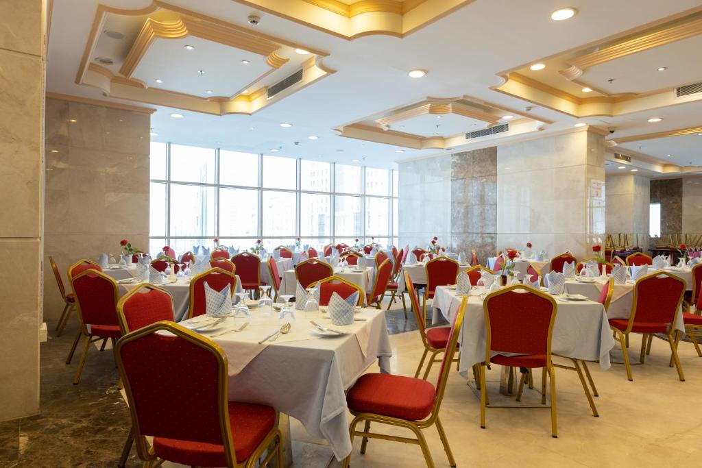 um salão de banquetes com mesas brancas e cadeiras vermelhas em Al Rayyan Towers 4 em Meca