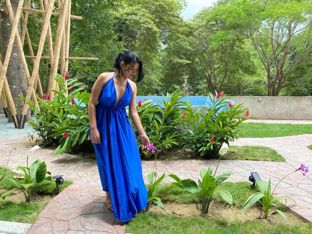 Una mujer con un vestido azul parada en un jardín en Tayrona Suites, en El Zaino