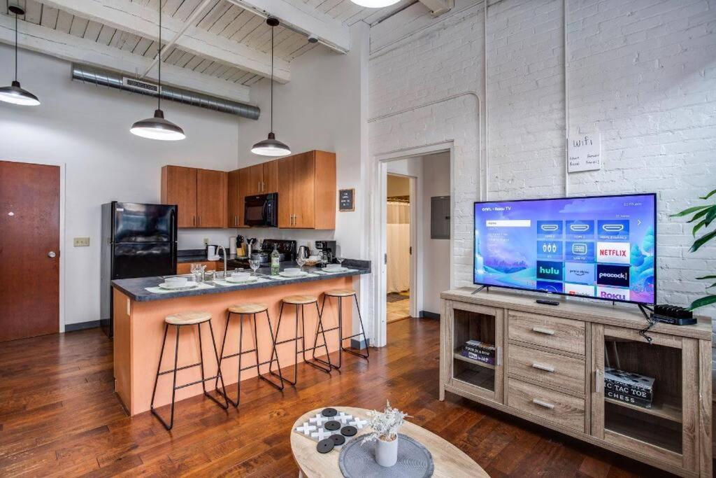 a living room with a tv and a bar with stools at NY Style Centric Loft w/ KingBed in Rochester