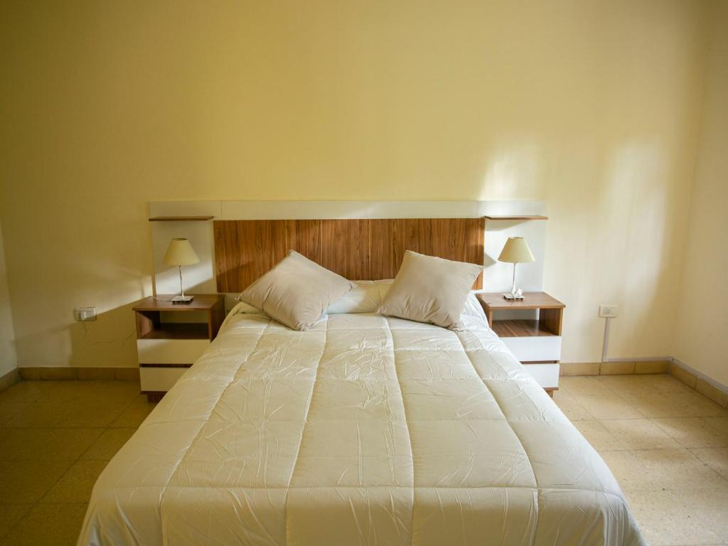 a bedroom with a large white bed with two night stands at La Casa de la Plaza in San Antonio de Areco