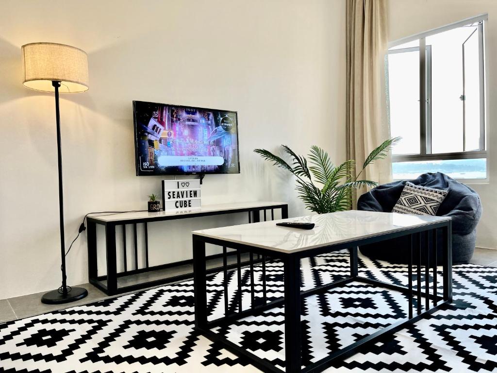 uma sala de estar com uma mesa e uma televisão em Langkawi Seaview Cube w/ Rooftop Pool em Kuah