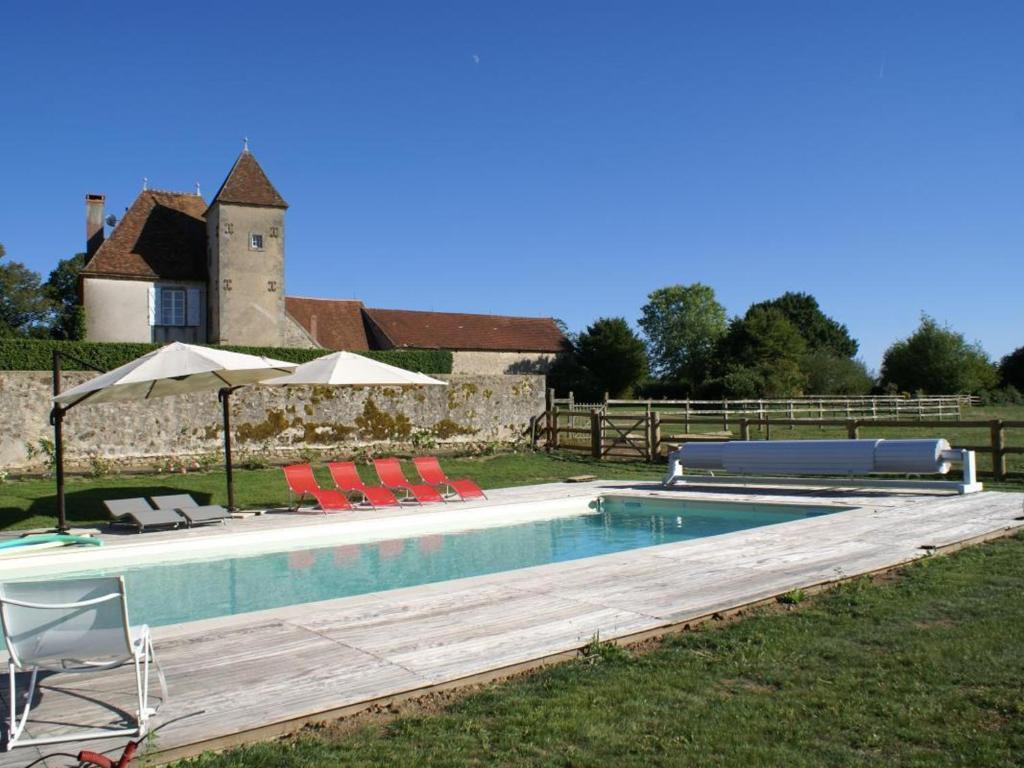 una piscina con sillas y sombrillas junto a una casa en Gîte Le Brethon, 5 pièces, 8 personnes - FR-1-489-217, en Le Brethon