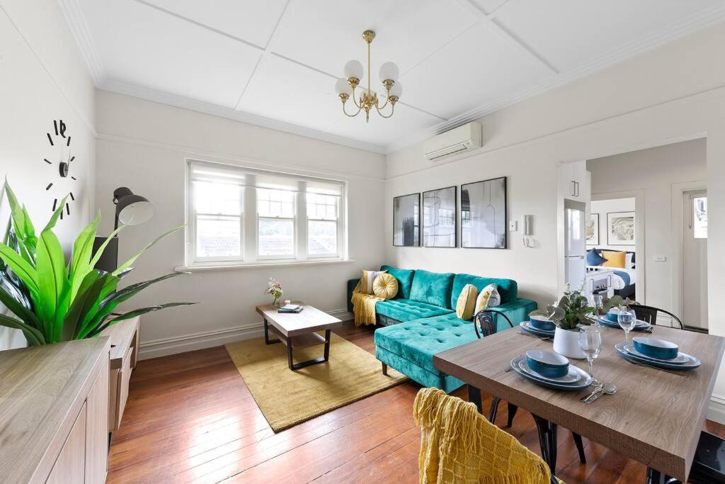 Una sala de estar con un sofá azul y una mesa. en Art Deco Hideaway - St Kilda, en Melbourne