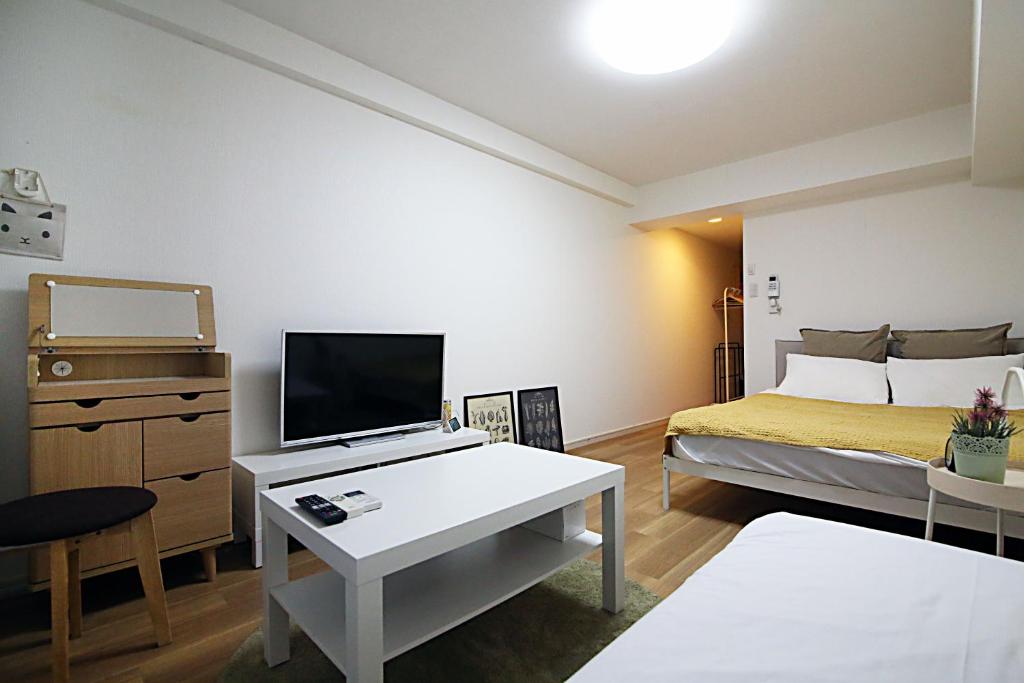 a bedroom with a bed and a table with a tv at GM Shinjuku in Tokyo